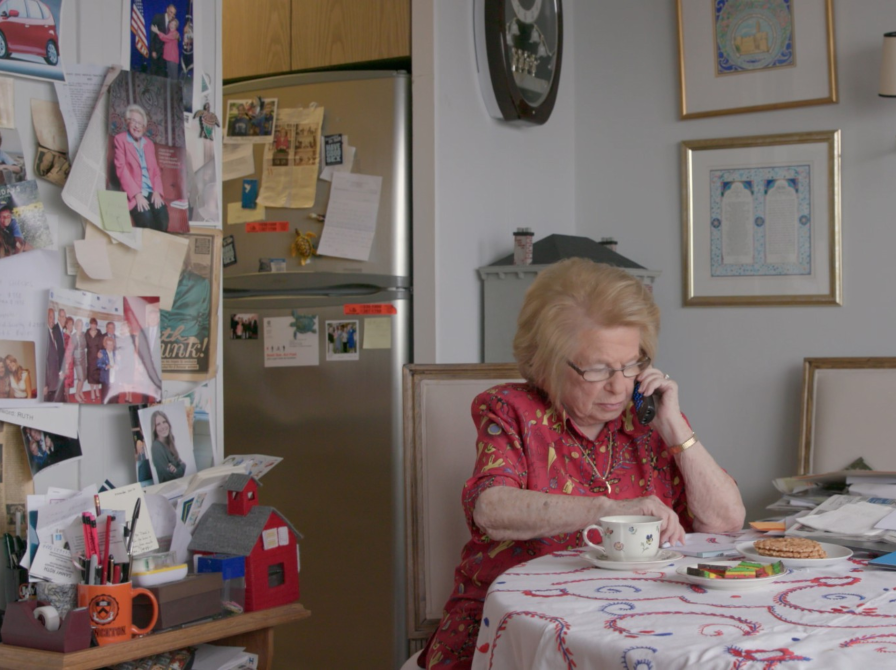 Ruth ved sit køkkenbord taler i telefon